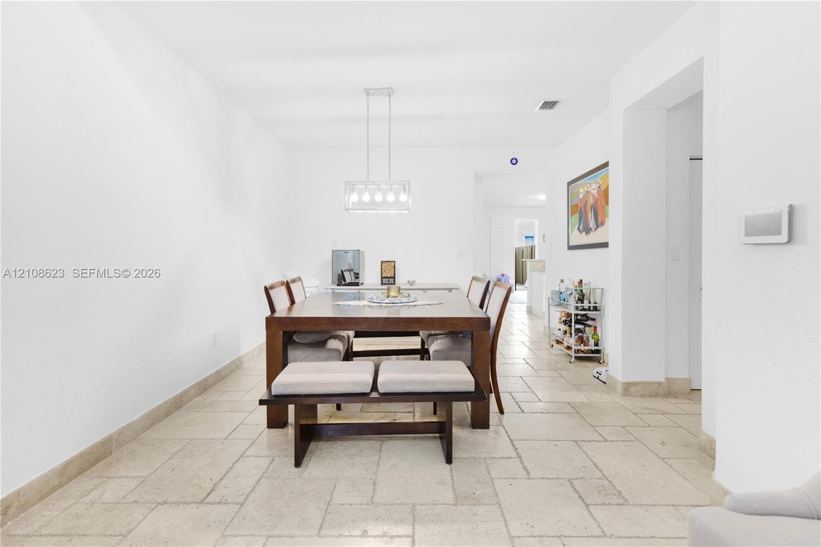Natural stone flooring in a rectangular tile pattern, finished with a contemporary multi-light linear pendant fixture
