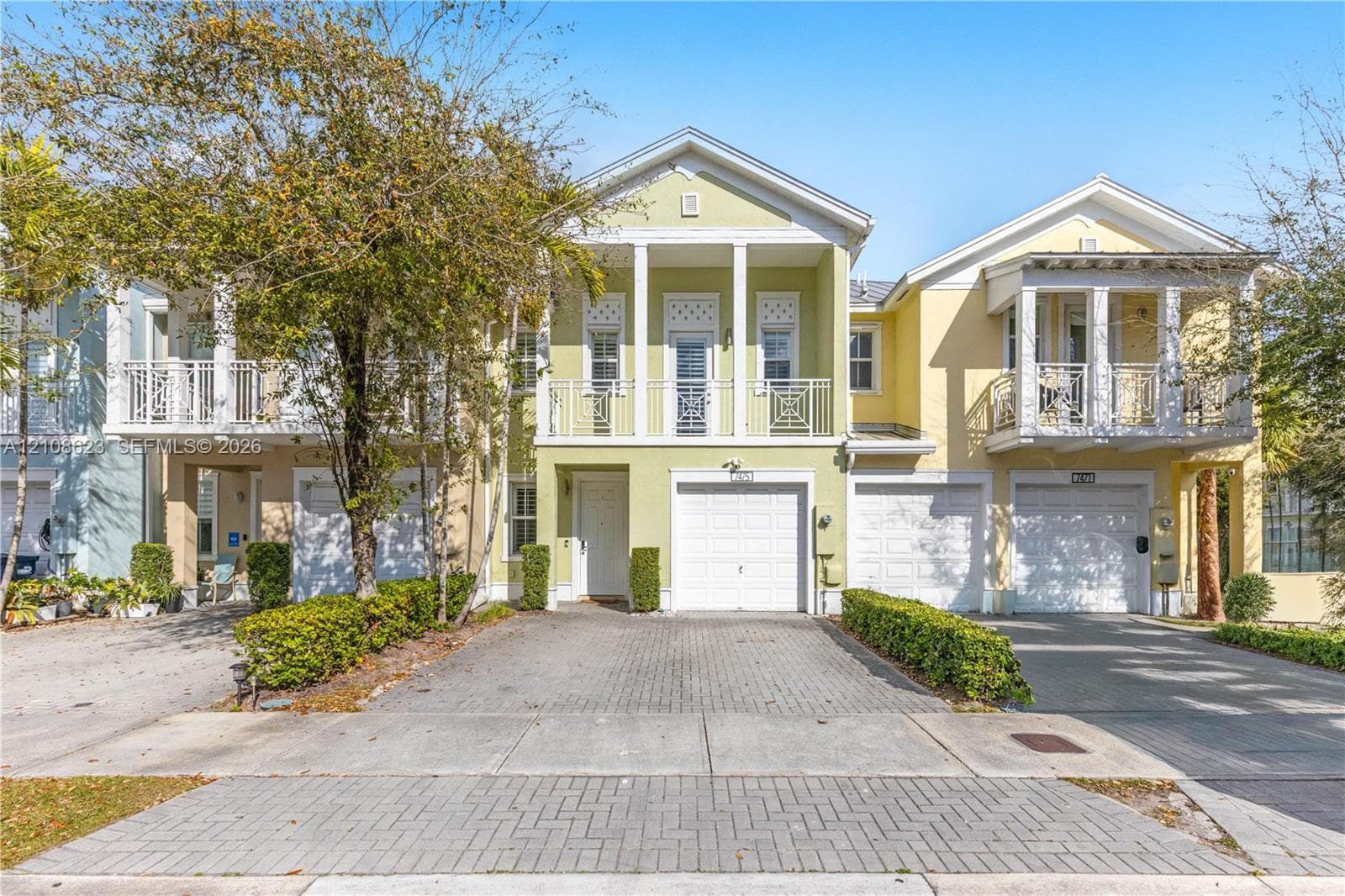 Two-story residence featuring a paved driveway, attached garage, second-level balcony with decorative railing, and columned architectural detailing