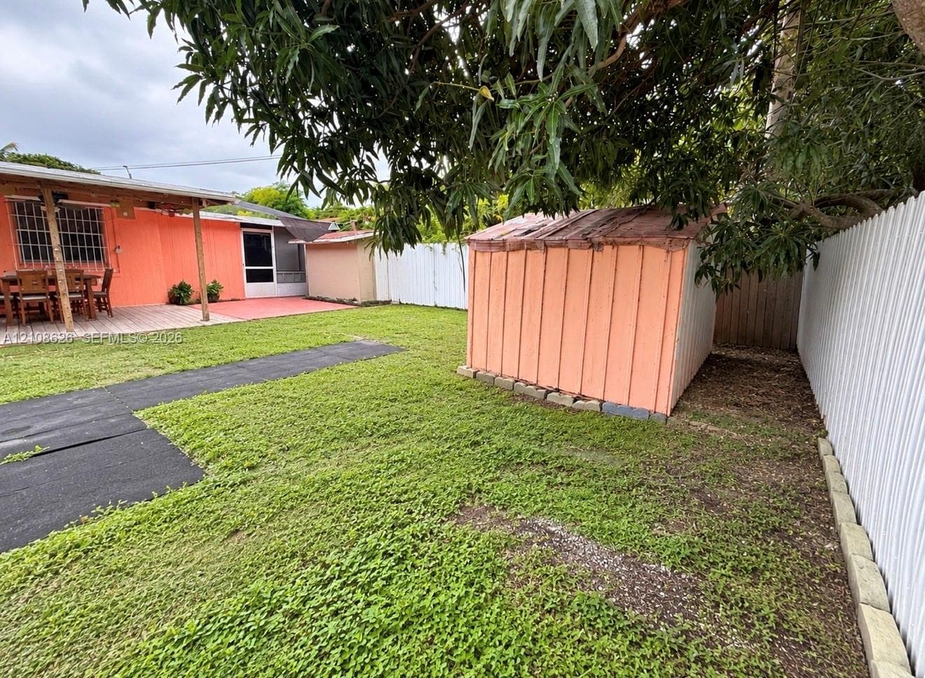 Backyard featuring a grass lawn, a detached storage structure, a paved patio, and perimeter fencing