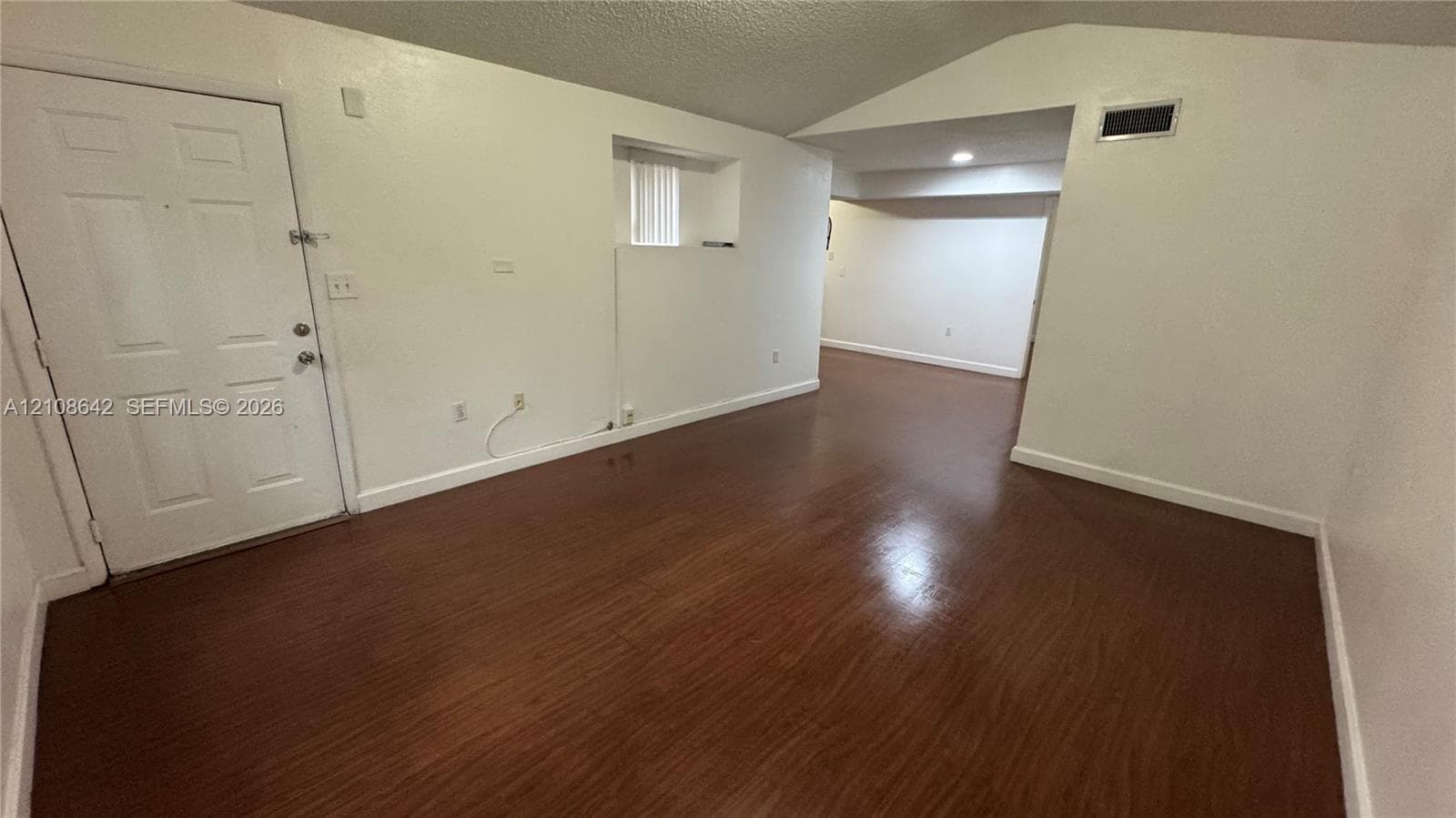 Interior space featuring wood-finish flooring, vaulted ceiling, and white panel door