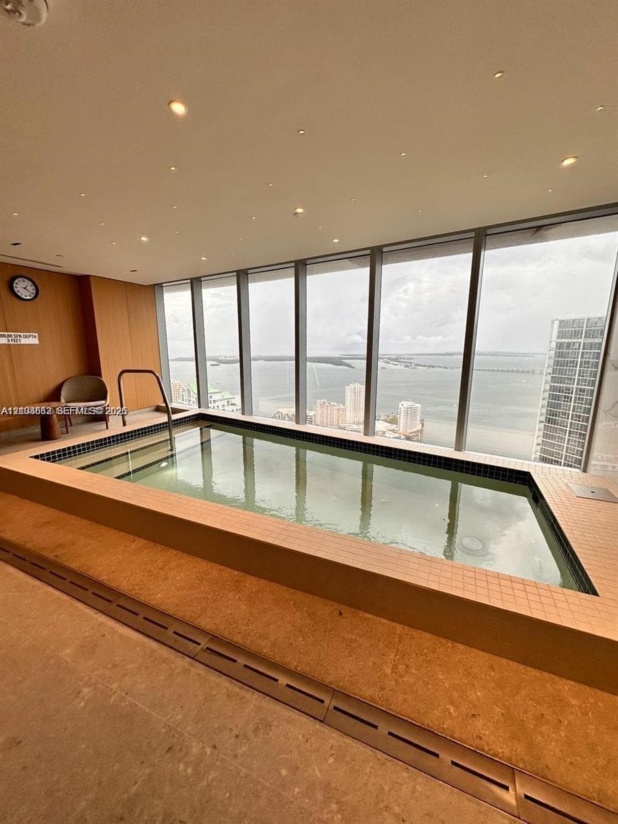 Indoor pool featuring floor-to-ceiling windows, tile surround, recessed lighting, and wood-paneled walls