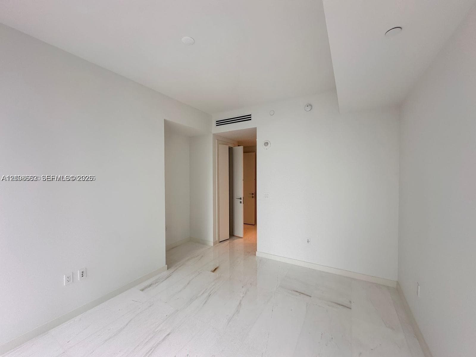 Interior space featuring polished stone-finish flooring, neutral wall finishes, recessed ceiling lighting, and a doorway with a swinging door