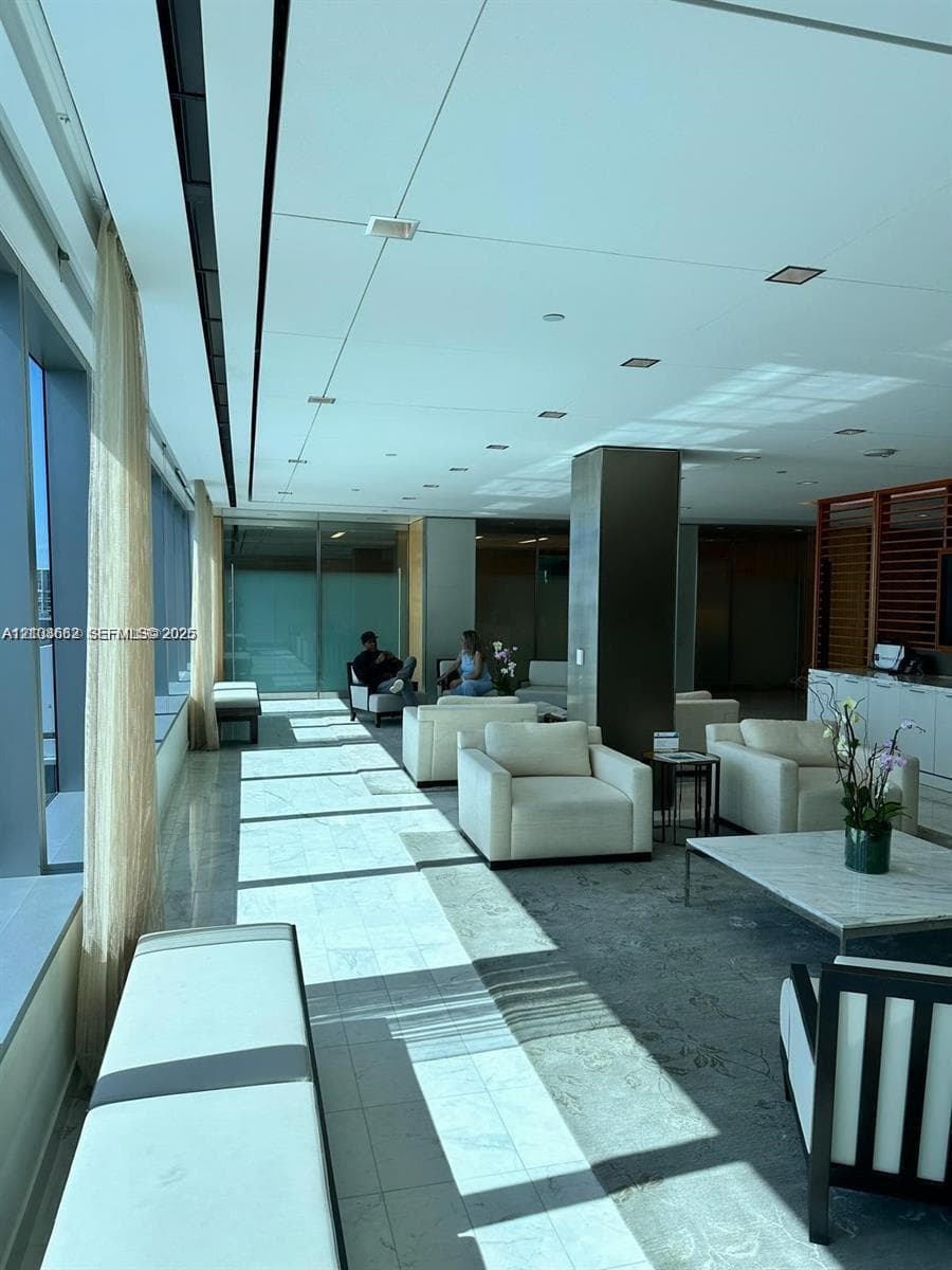 Open-concept common area featuring floor-to-ceiling windows, polished stone flooring, recessed ceiling lighting, and a prominent structural pillar
