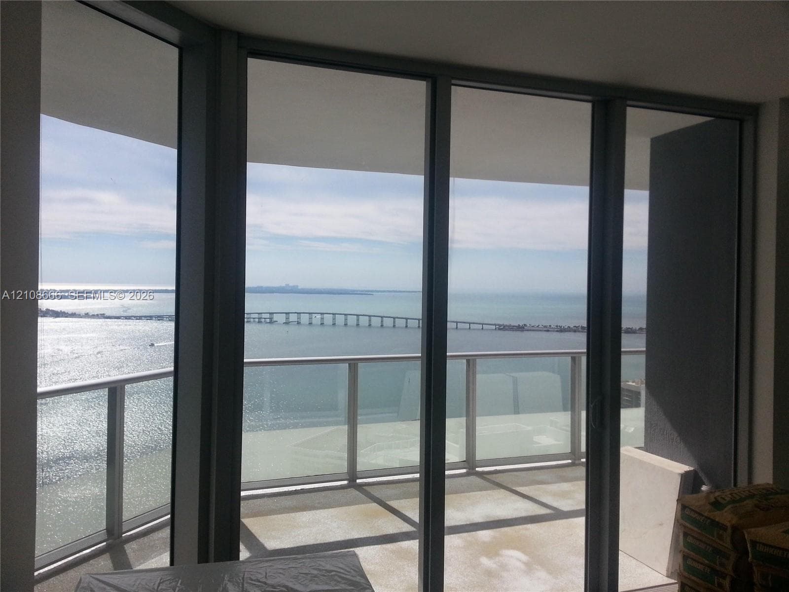 Floor-to-ceiling glass panel windows, metal-framed sliding glass doors, and a private balcony with a glass railing