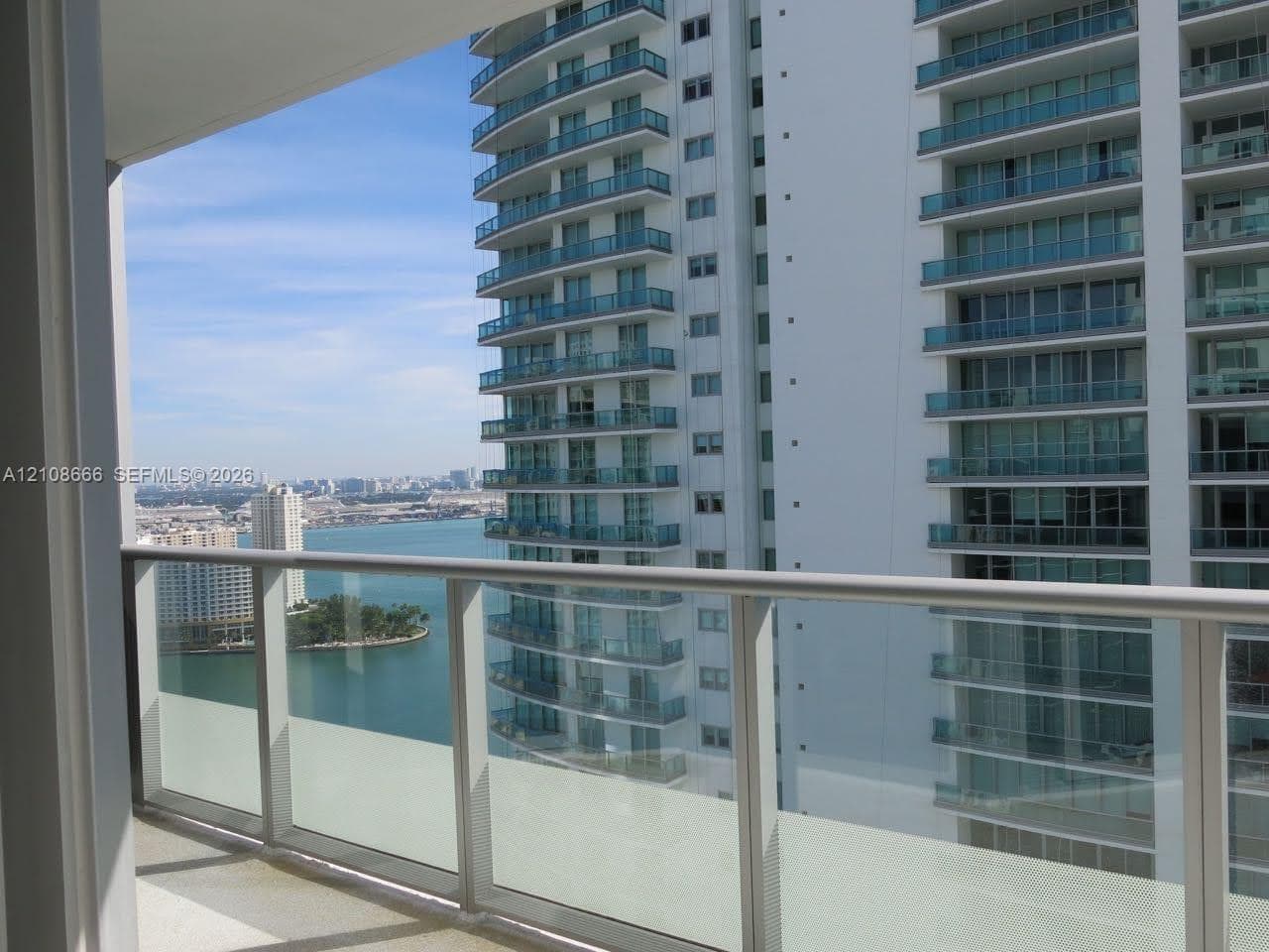 Private balcony with a glass and metal railing, concrete flooring, and water scenery