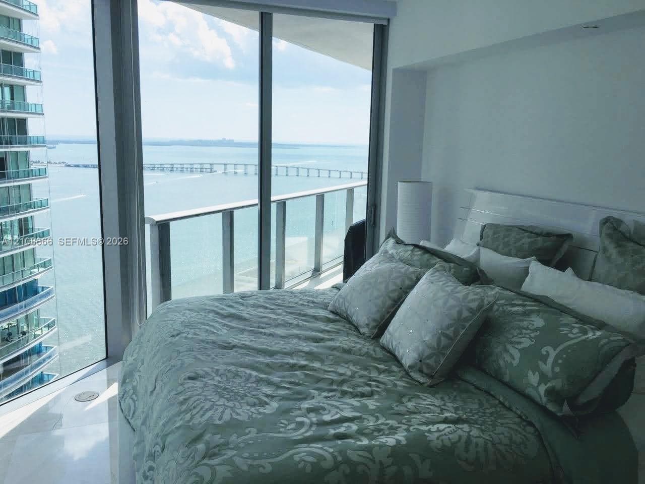 Floor-to-ceiling windows, attached glass-railed balcony, and polished stone flooring