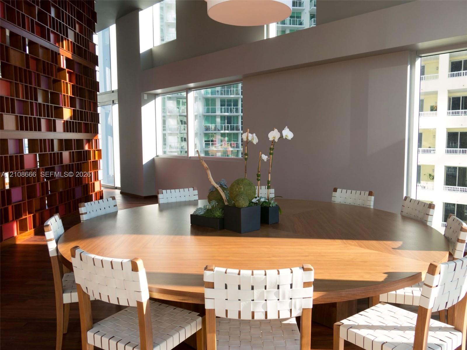 Double-height ceilings, floor-to-ceiling windows, and a floor-to-ceiling custom geometric wood-slat feature wall accented by wood-finish flooring