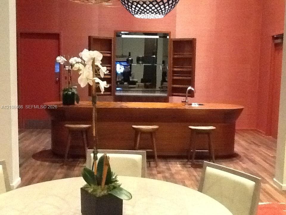 Custom wood-finished bar featuring a curved design, built-in shelving, a stainless steel sink, and wood-finish flooring