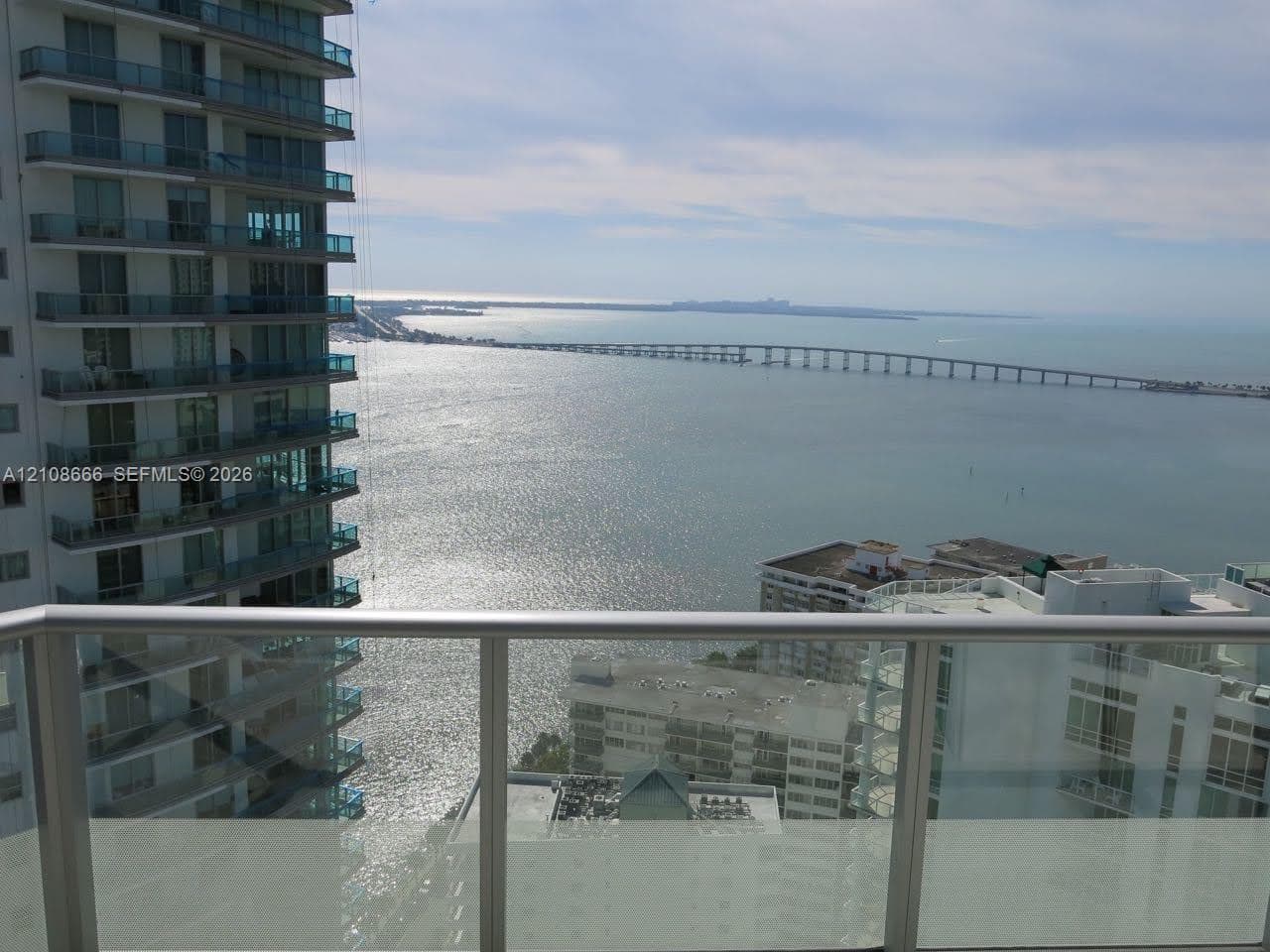 Balcony featuring glass railings, metal framing, and direct water and bridge scenery