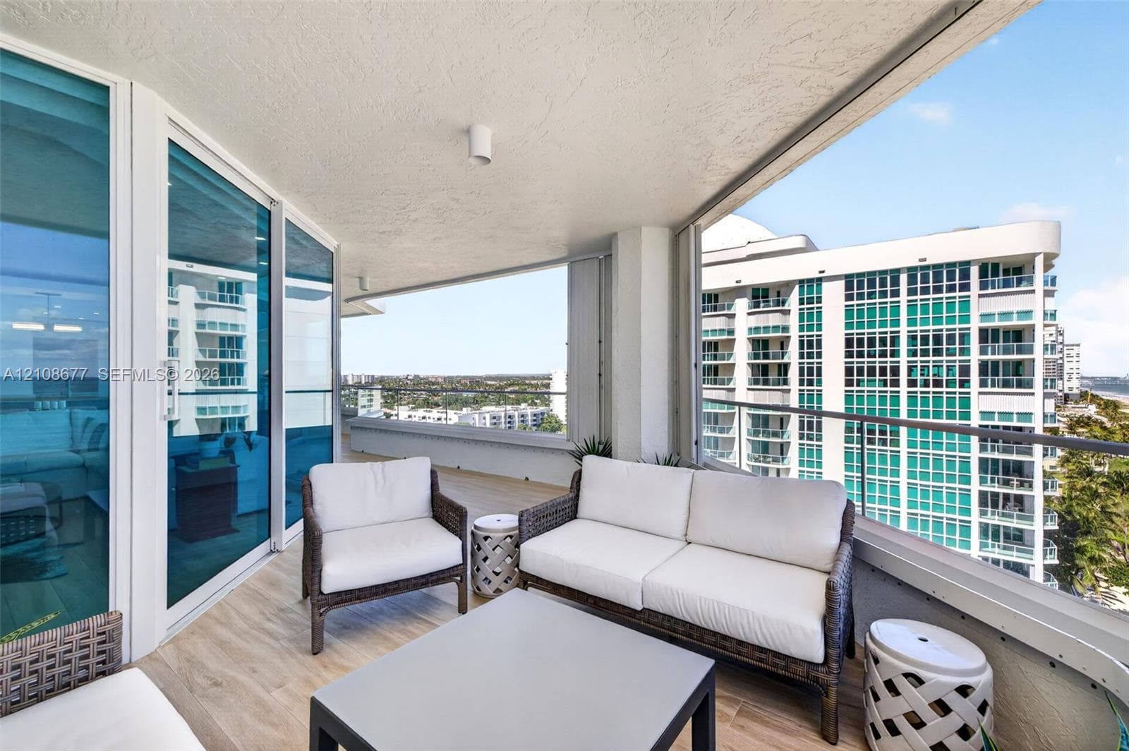 Covered balcony featuring wood look plank porcelain flooring, floor-to-ceiling glass paneling, and a metal railing. Additional protection for your furniture with upgraded accordion shutters.