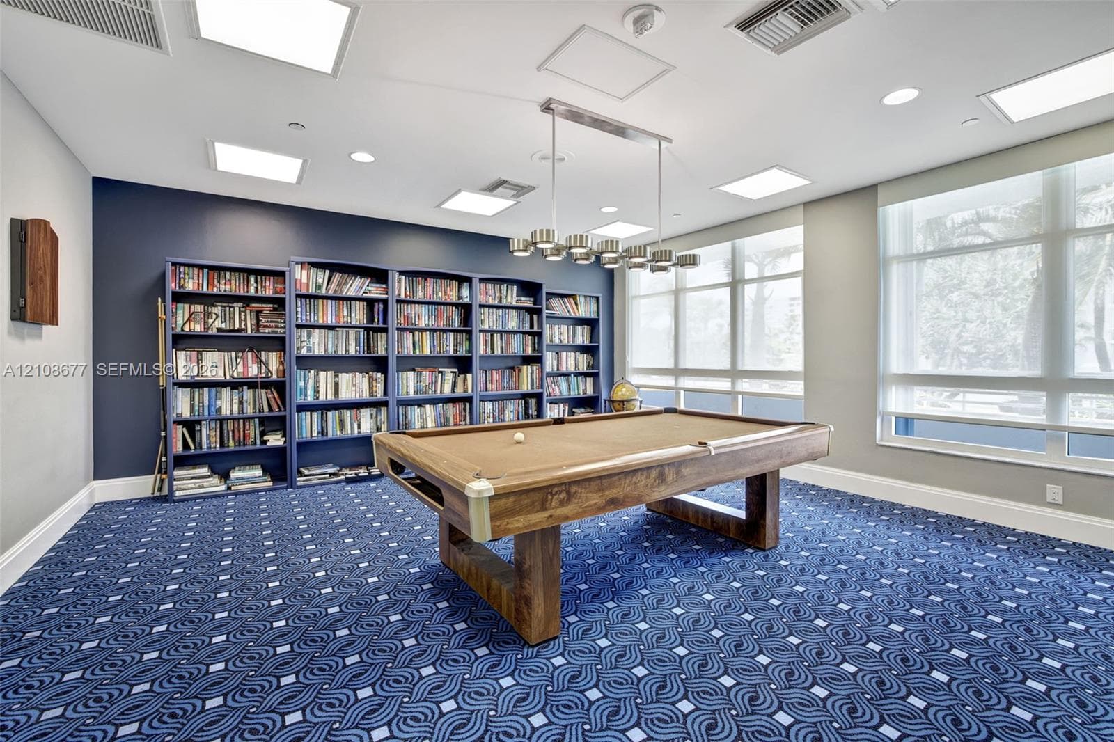 Game room / library in building w/ newer carpet, book shelving units, and pool table