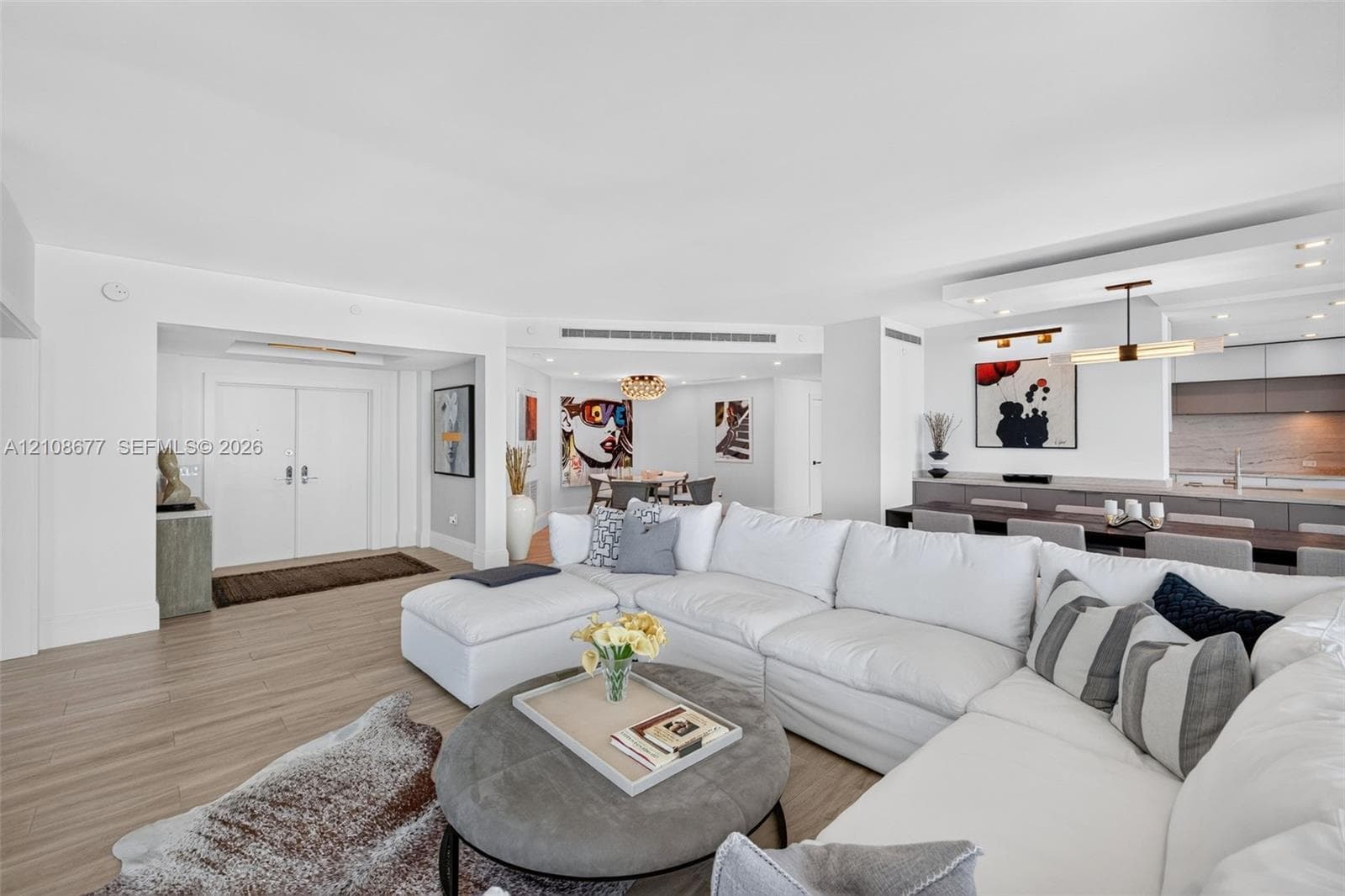 Open floor plan featuring wood look plank porcelain flooring, recessed lighting, double-door entry / foyer, and view toward the kitchen and stone wall backsplash