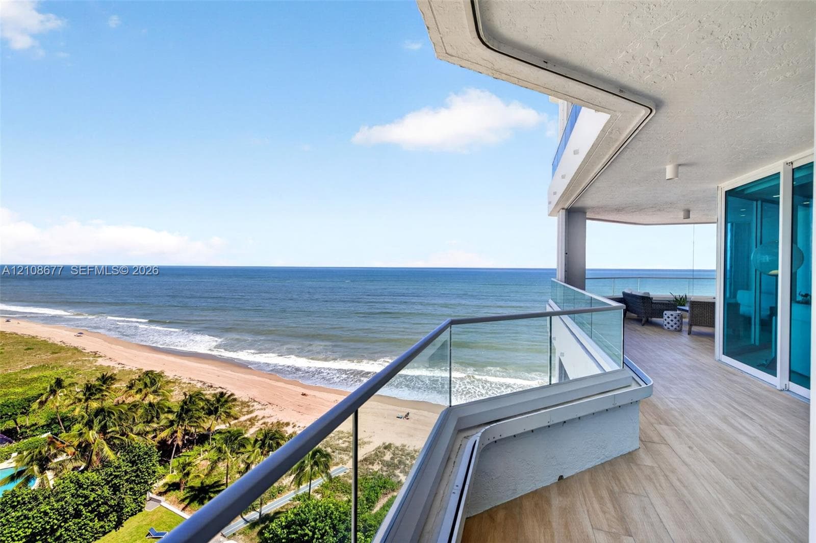Expansive wraparound balcony featuring glass panel railings, wood look plank porcelain flooring, recessed lighting, and direct oceanfront exposure. Additional protection for your furniture with upgraded accordion shutters.