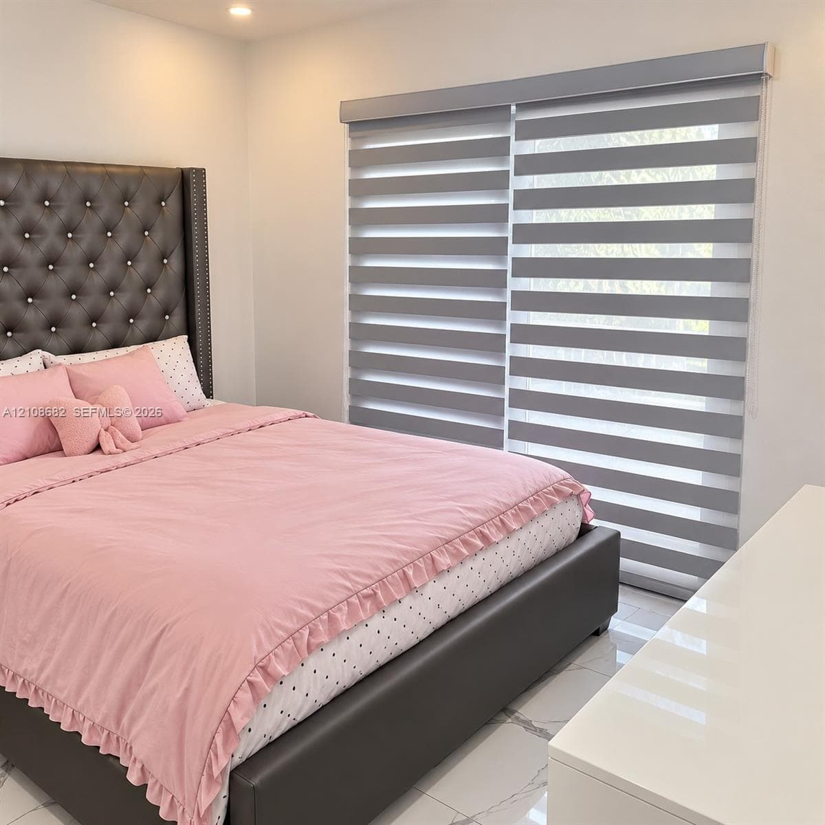 Recessed ceiling lighting, large-format polished tile flooring, and layered zebra roller shades