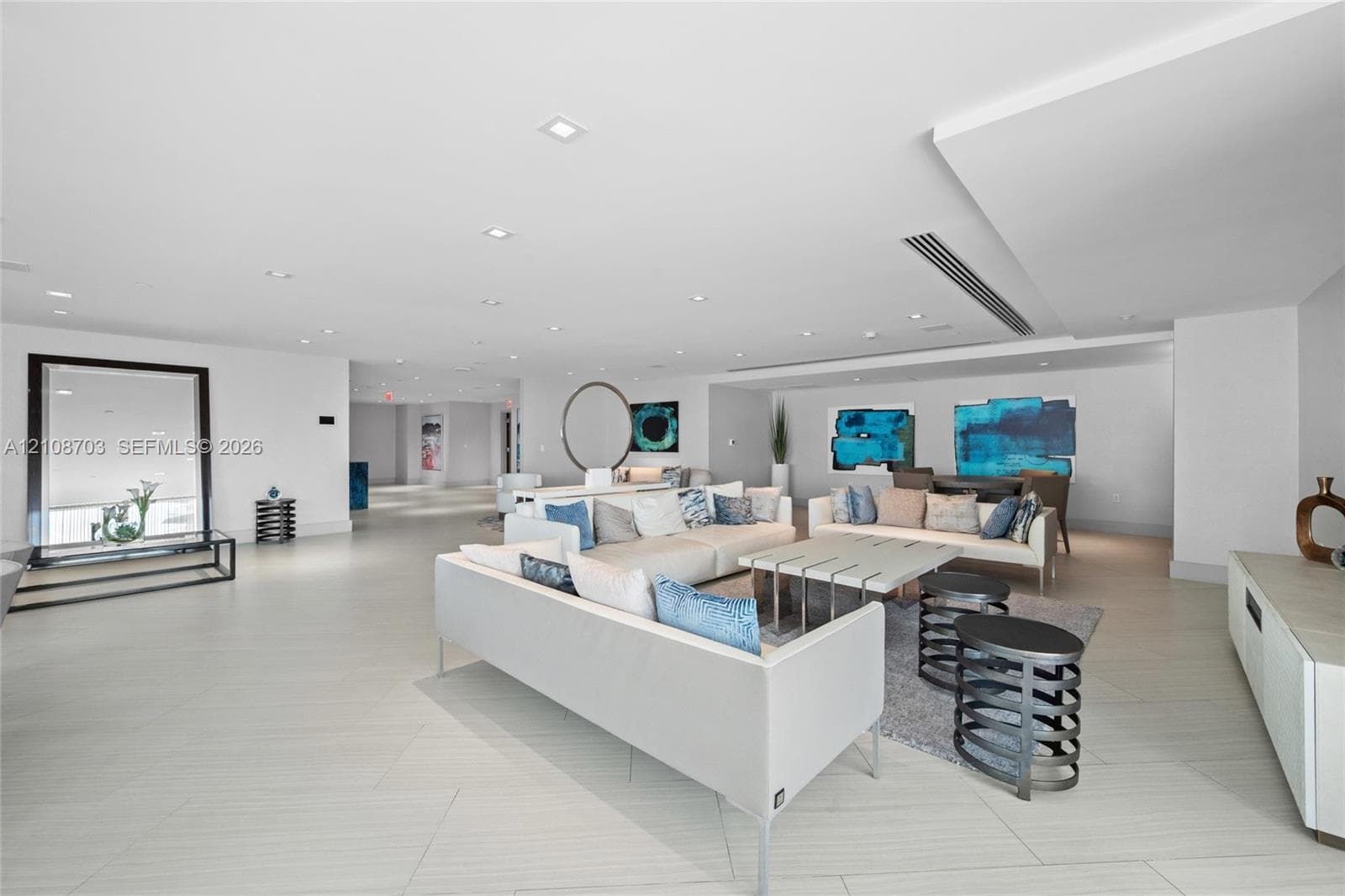 Expansive living area featuring porcelain tile flooring, recessed lighting, soffit ceiling detailing, and built-in linear HVAC registers