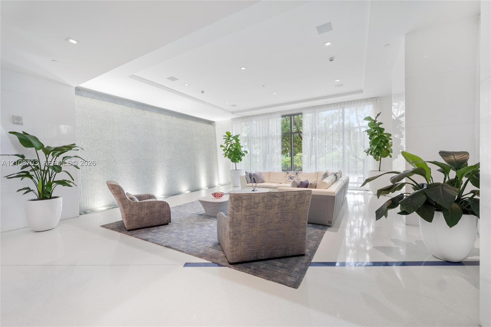 Expansive lobby featuring polished stone flooring, a full-height decorative tiled water feature with recessed accent lighting, recessed ceiling lighting, and floor-to-ceiling windows