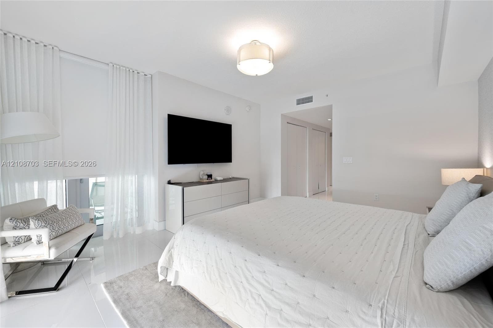 Bright bedroom featuring high-gloss tile flooring, floor-to-ceiling sheer window treatments, and a contemporary drum-style ceiling fixture