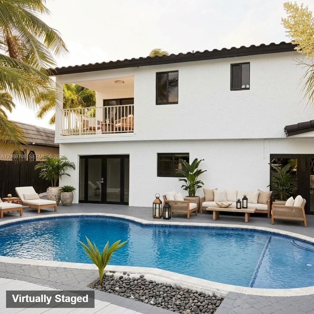 Two-story exterior featuring white stucco siding, a tiled roof, a covered second-story balcony with white railings, a swimming pool with stone-tiled edging, and grey paver hardscaping