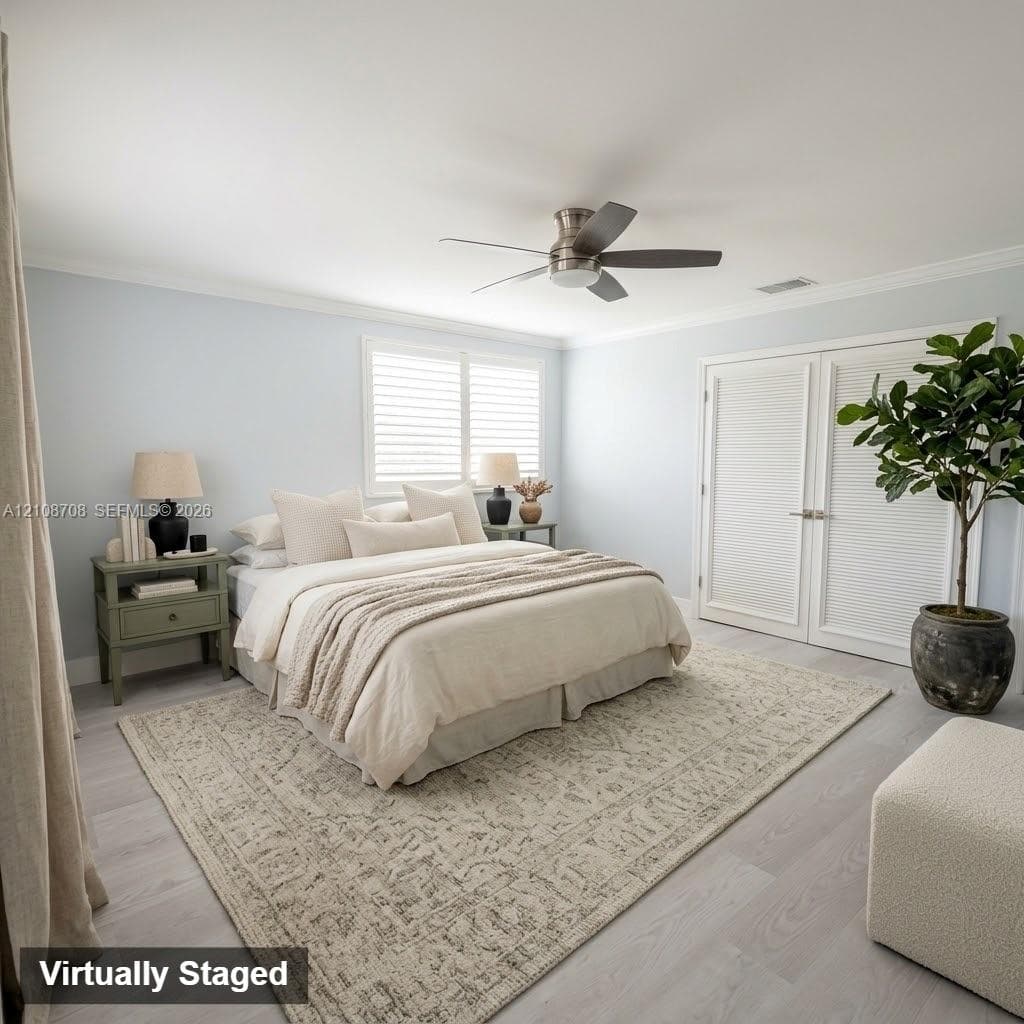 Neutral-toned interior featuring wood-finish flooring, plantation shutters, crown molding, and a satin nickel ceiling fan with integrated lighting