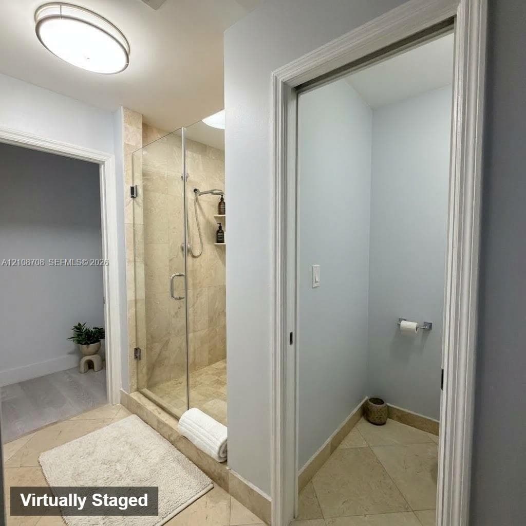 Walk-in shower with frameless glass enclosure, stone-tile surround, and built-in shelving, complemented by stone-tile flooring and an oval flush-mount ceiling light
