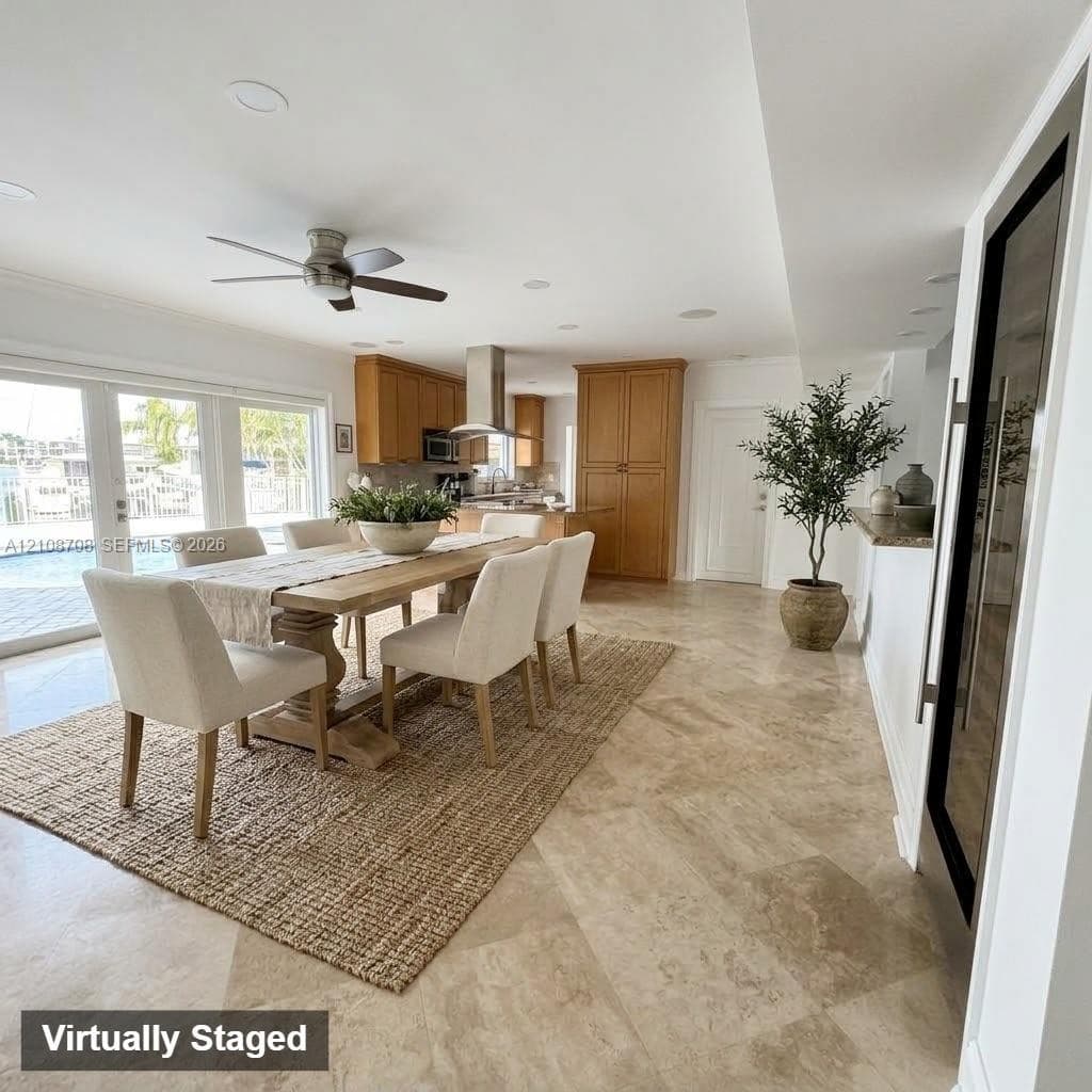 Open-concept floor plan featuring large-format stone flooring, wood cabinetry, built-in wine refrigeration, and glass paneled doors opening to the exterior