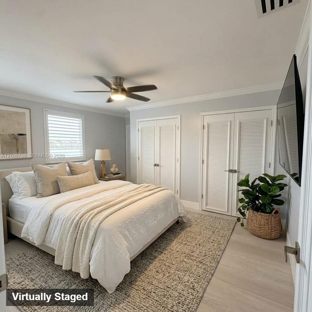 Neutral interior featuring wood-finish flooring, ceiling fan with integrated lighting, louvered-style double closet doors, and window shutters
