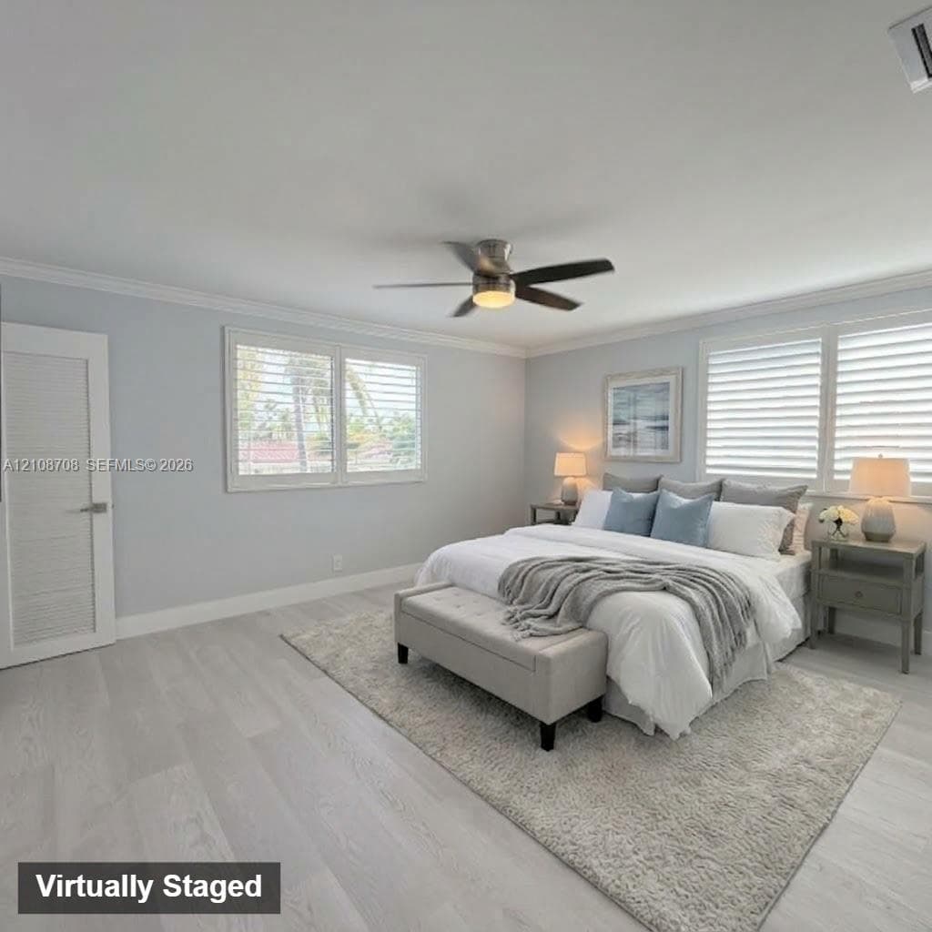 Neutral-toned interior featuring wood-finish flooring, crown molding, tiered plantation shutters, and a central ceiling fan with an integrated light fixture