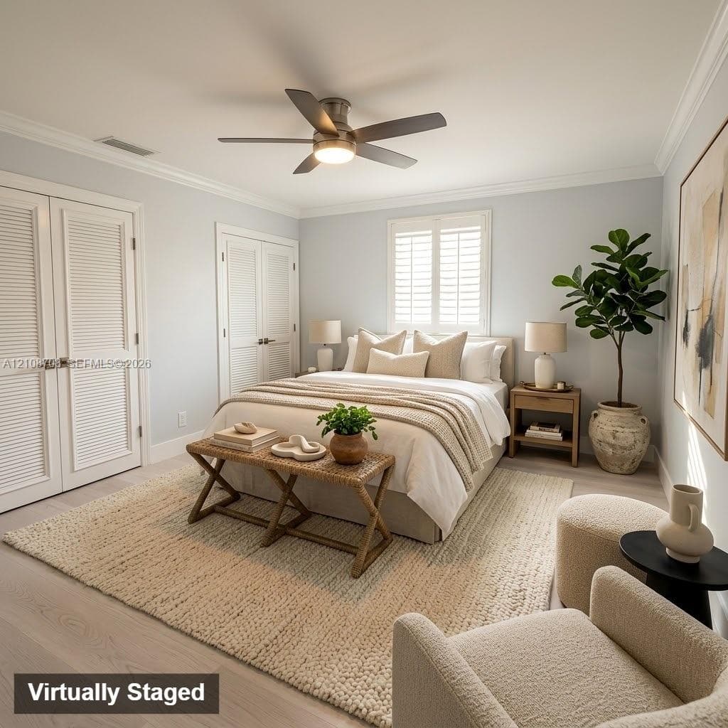 Neutral-toned interior featuring wood-finish flooring, white louvered closet doors, a multi-blade ceiling fan with integrated lighting, and plantation shutters