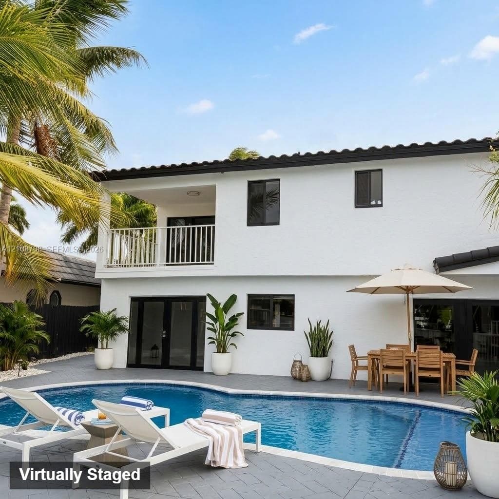 Stucco exterior featuring a second-story balcony with metal railings, a covered patio, and a private in-ground swimming pool surrounded by paved hardscaping