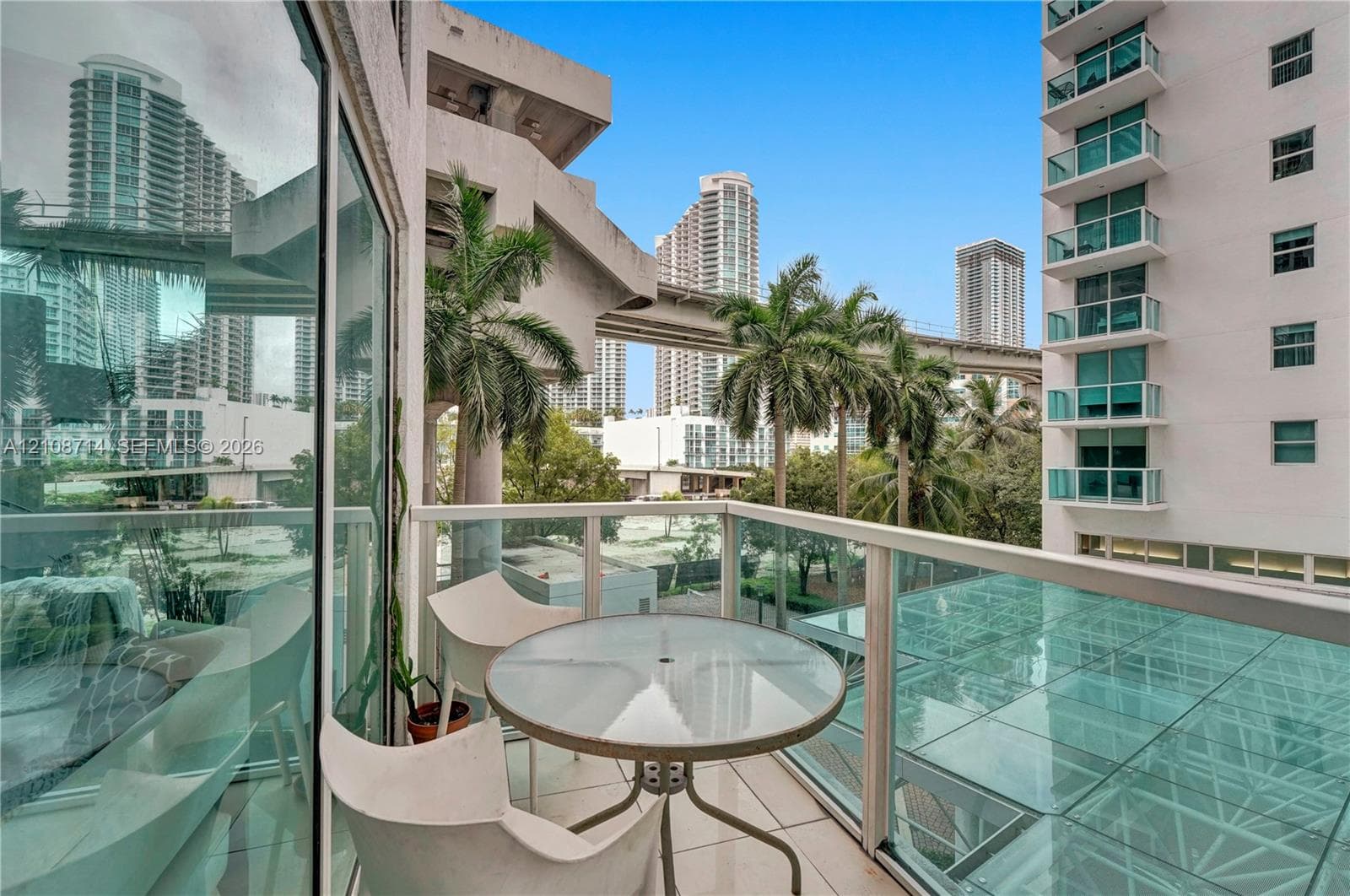 Private balcony featuring glass-panel railings, light-toned floor tile, and floor-to-ceiling glass wall
