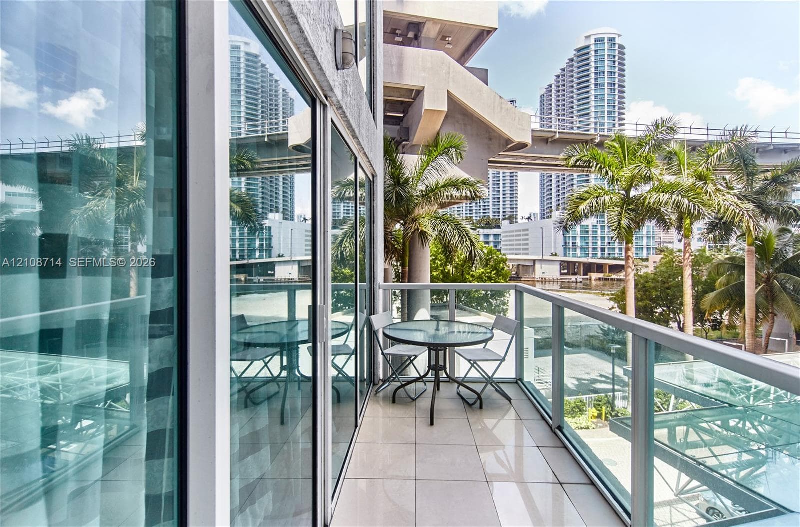 Private balcony featuring large-format tile flooring, a glass-panel railing, and full-height floor-to-ceiling sliding glass doors