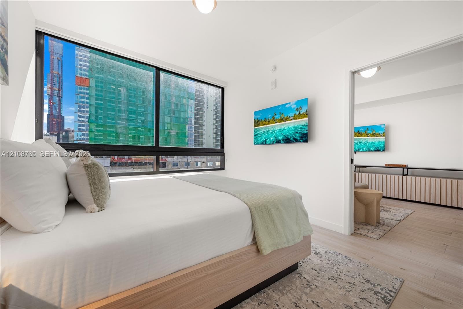 Floor-to-ceiling windows with dark frames, wood-finish flooring, and minimalist white walls