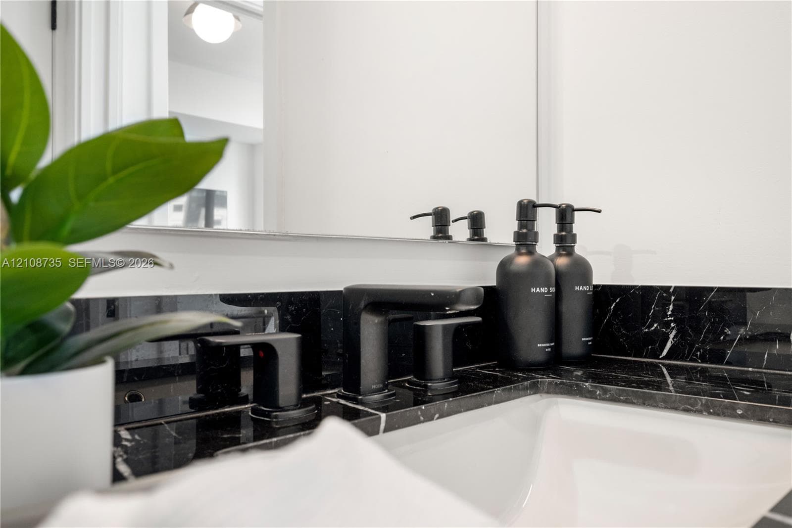Vanity featuring a dark stone countertop, undermount sink, matte black widespread faucet, and a large wall-mounted mirror