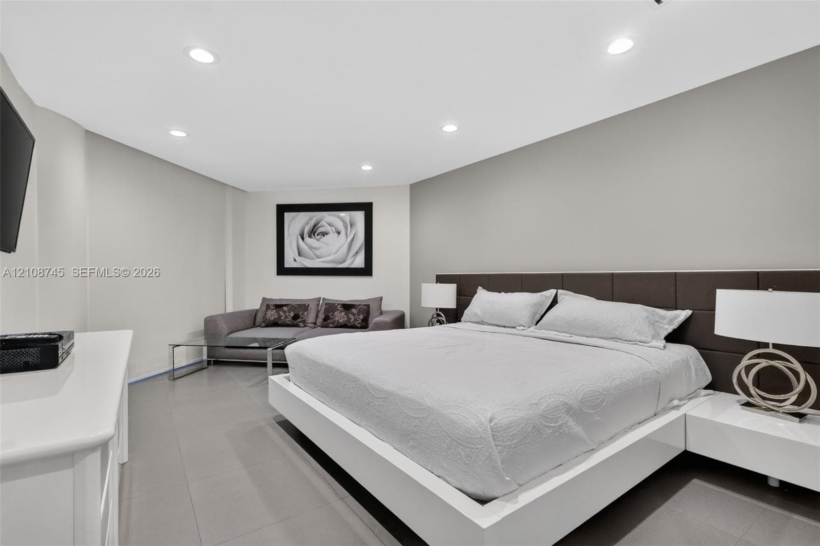 Recessed lighting, smooth-finish neutral walls, and large-format tile flooring