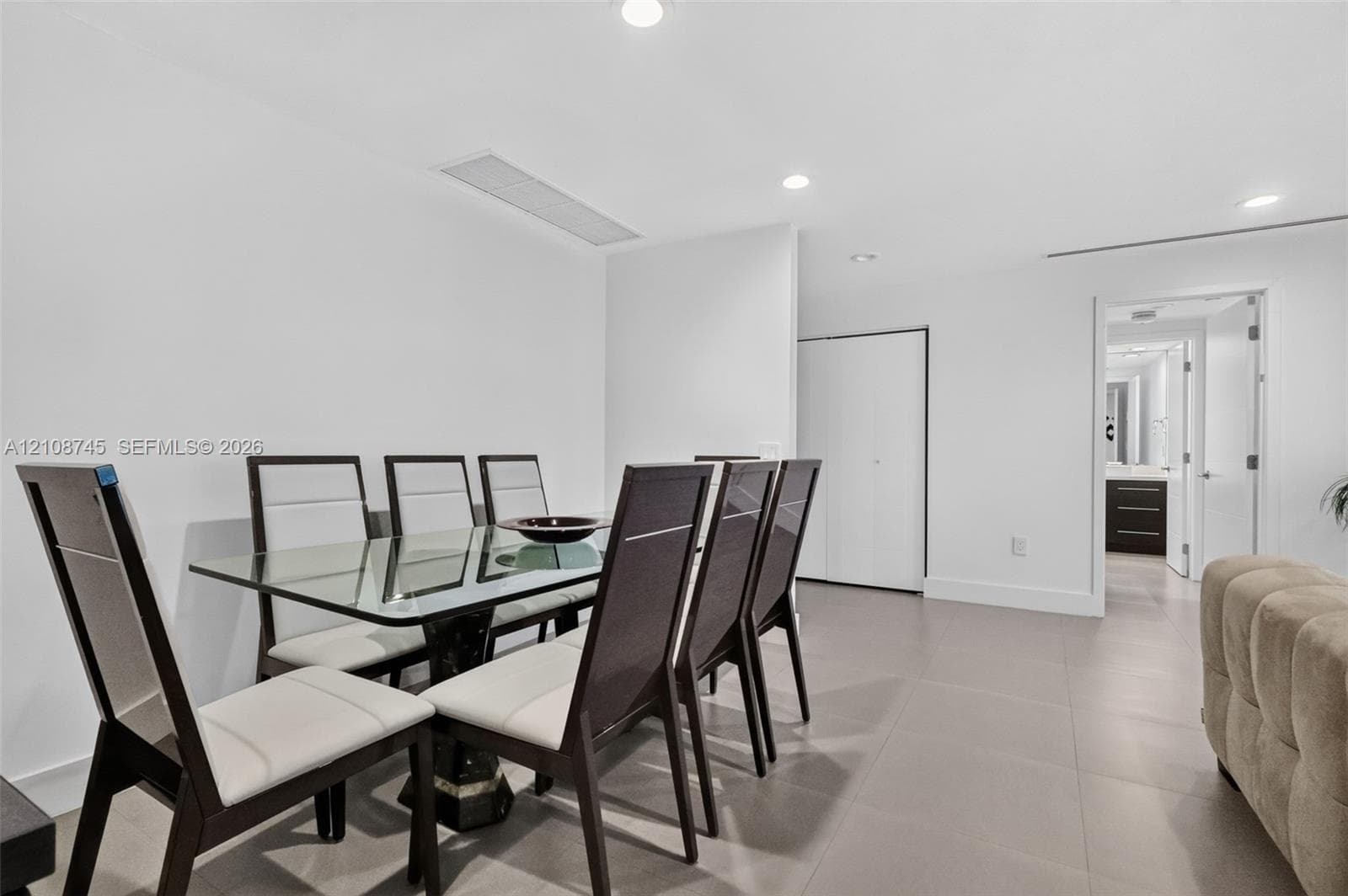 Neutral interior featuring smooth white walls, recessed ceiling lighting, and large-format tile flooring with a closet featuring white bi-fold doors