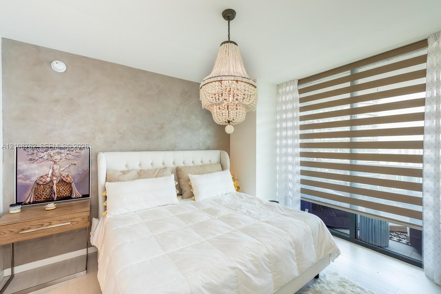 Beaded chandelier fixture, textured accent wall, and horizontal dual-layer privacy blinds