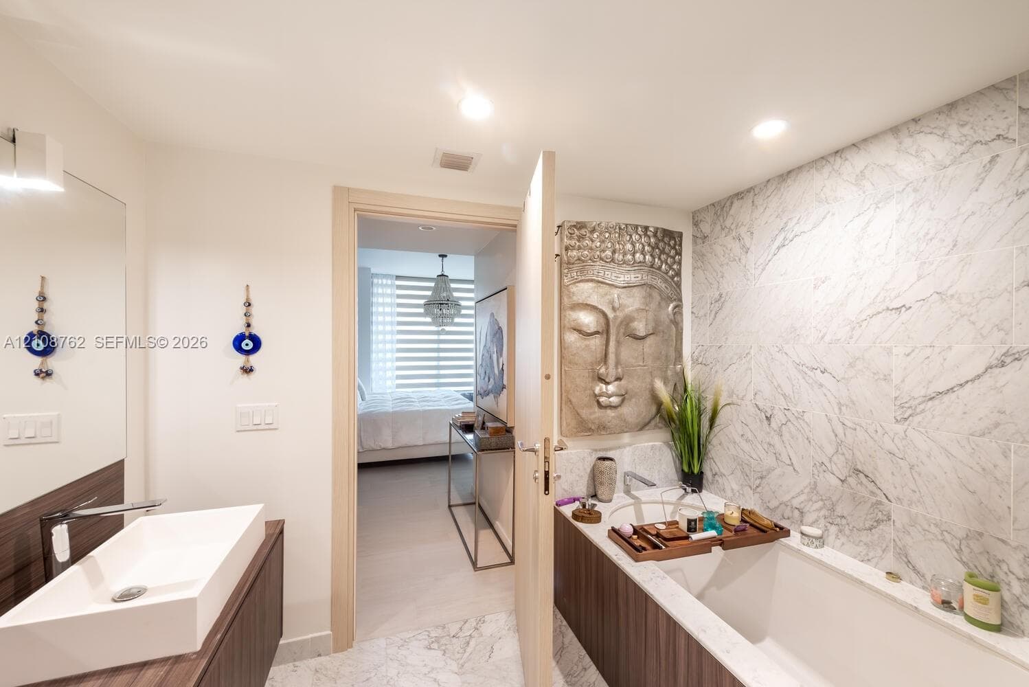 Floating vanity with rectangular vessel sink, stone-finish wall tiling, recessed lighting, and integrated soaking tub