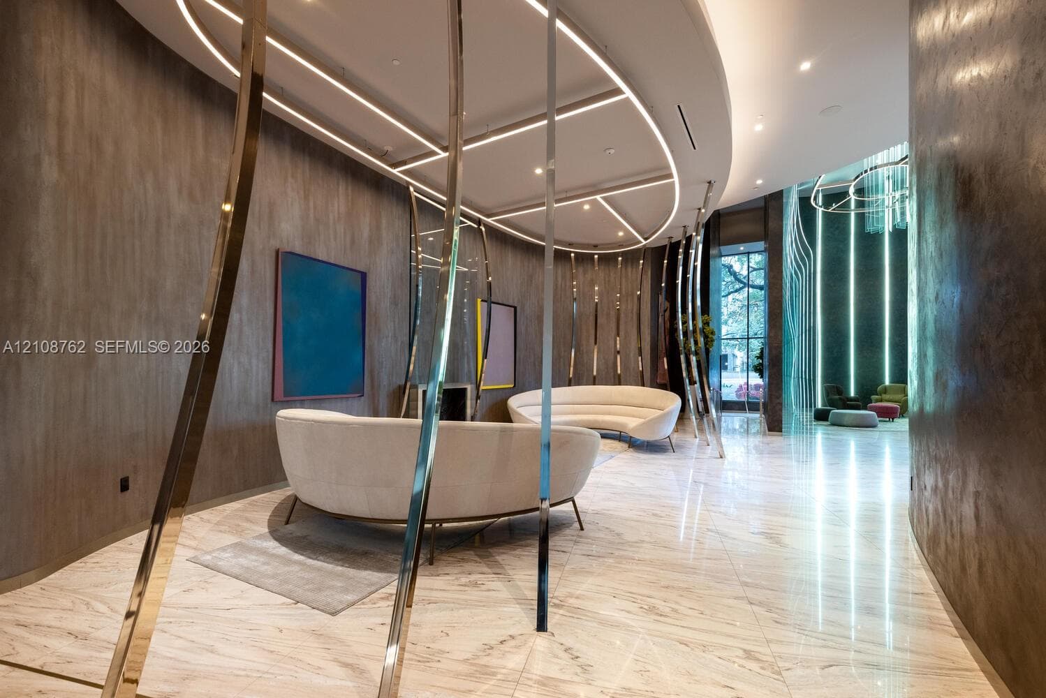 Polished stone flooring, textured wall finishes, custom curved ceiling architecture, integrated linear cove lighting, and polished metal decorative structural elements