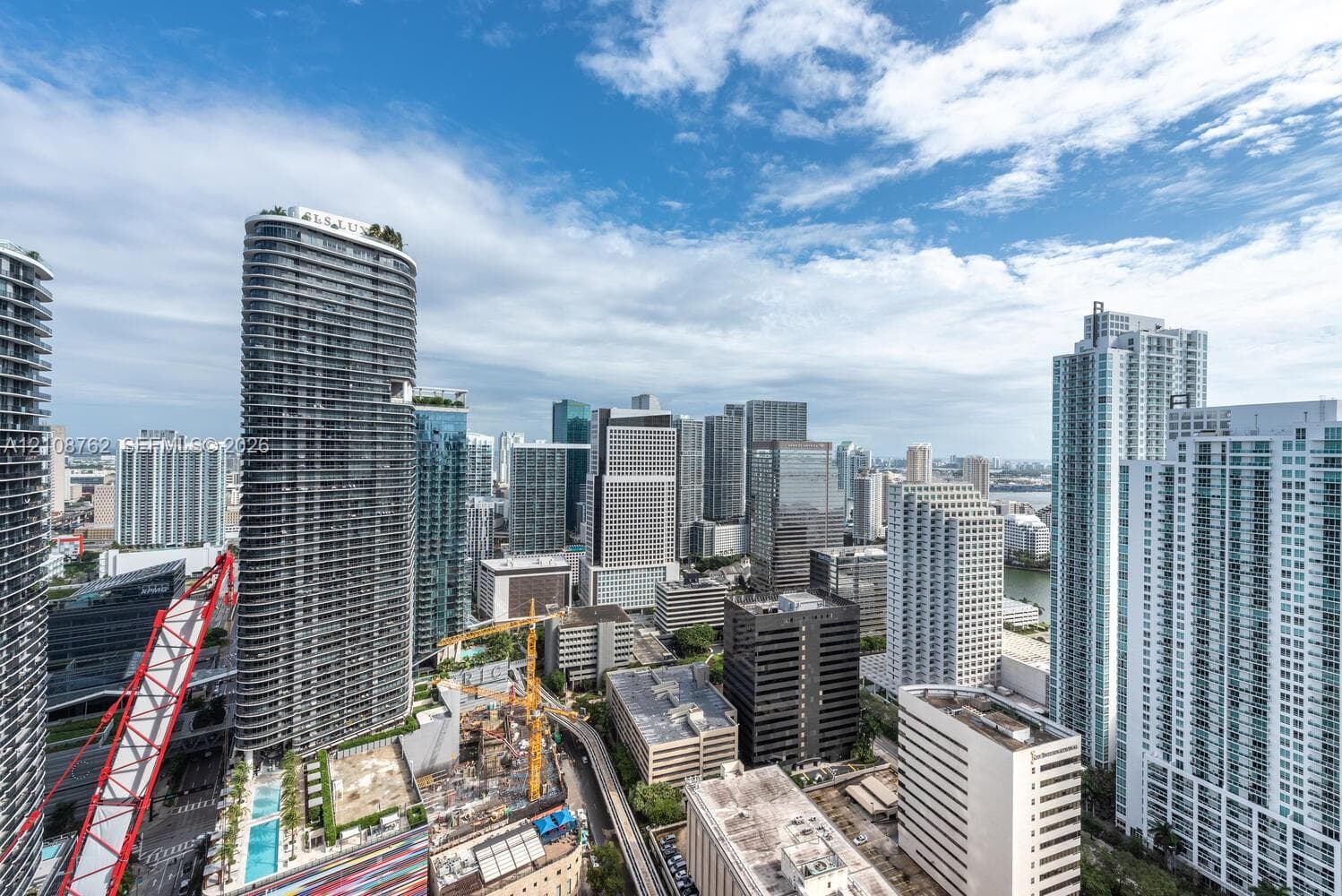 High-rise urban landscape featuring glass-facade skyscrapers, dense metropolitan architecture, and glimpses of the bay