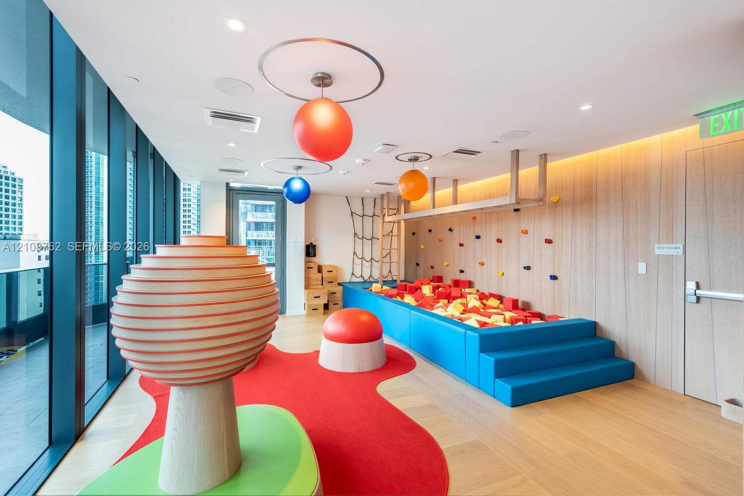 Floor-to-ceiling windows, wood-finish flooring, recessed lighting, and wall-mounted climbing wall feature