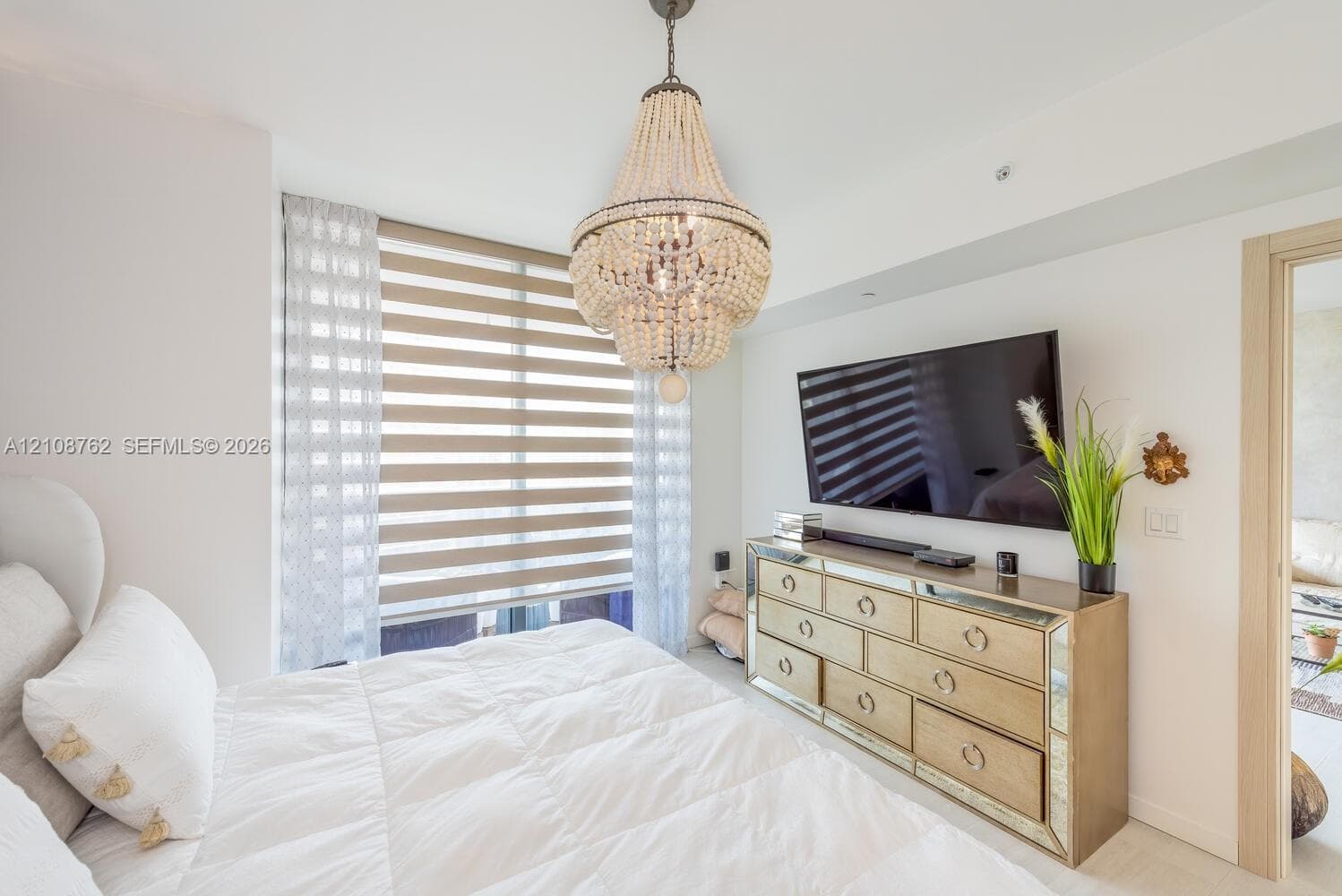 Beaded chandelier fixture, large window with layered window treatments, and light-tone interior finishes