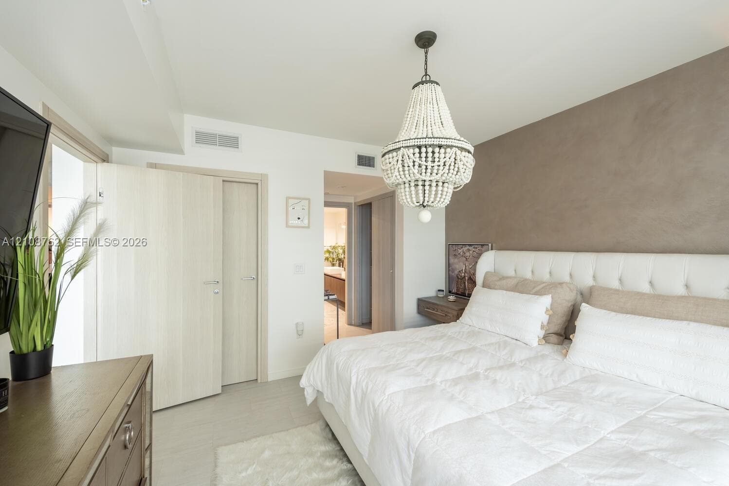 Beaded chandelier fixture, textured accent wall, and light-finish interior doors