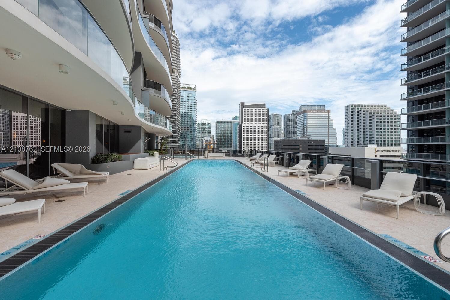 Lap pool featuring light-toned paved decking and glass perimeter railings