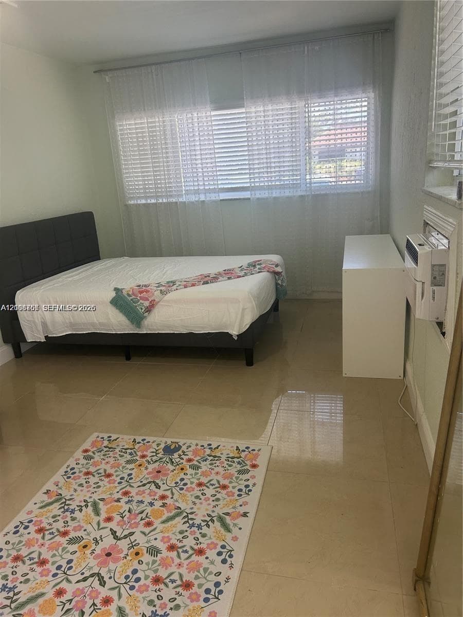 Large-format neutral tile flooring throughout with horizontal blind window treatments