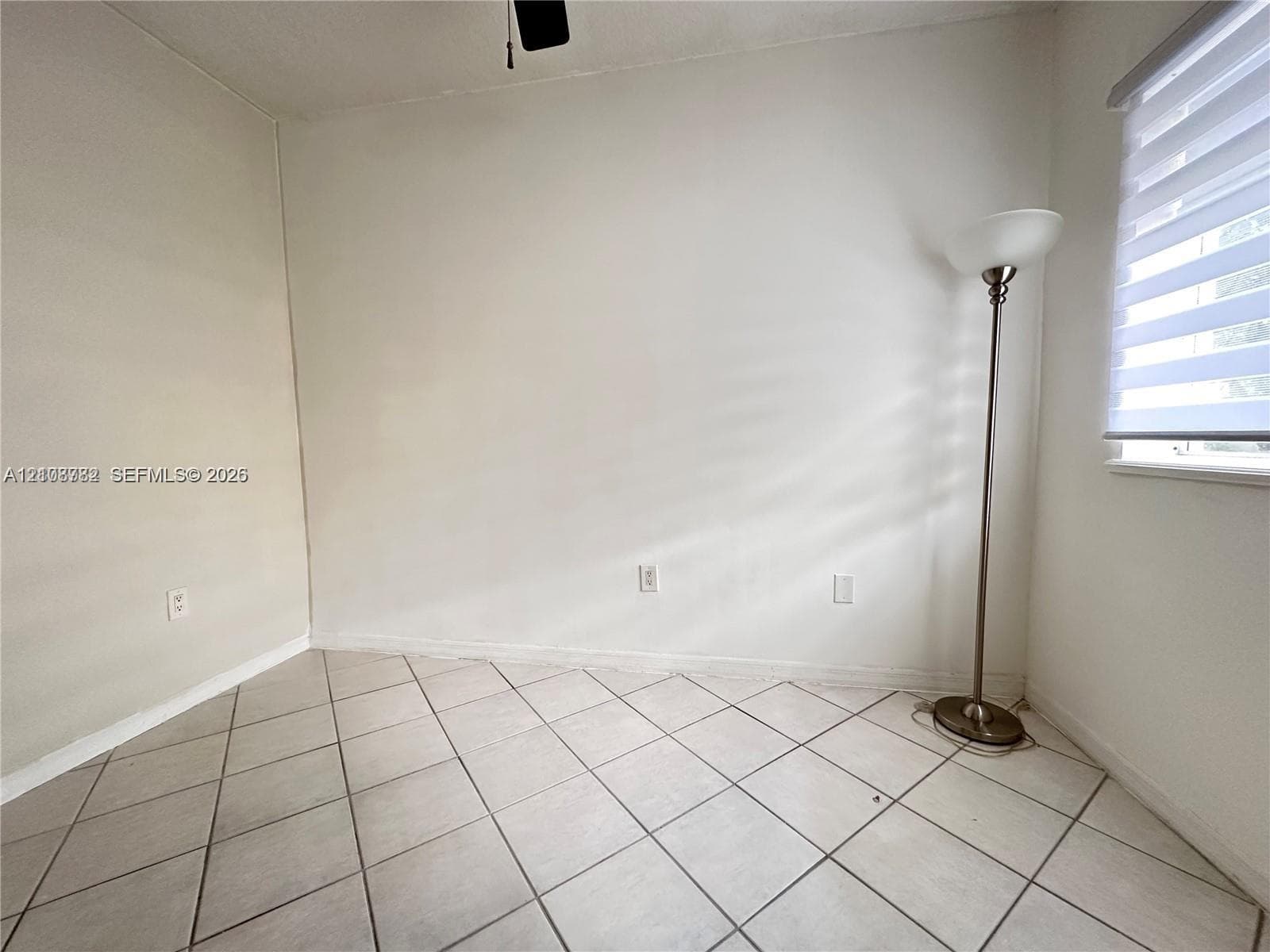 Neutral wall color, light-colored tile flooring set on a diagonal, and dual-layered window blinds