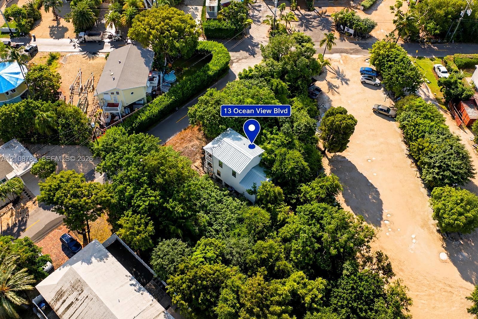 Aerial perspective of a multi-story residence featuring a metal roof, nestled within a lot characterized by mature tree canopy and established vegetation