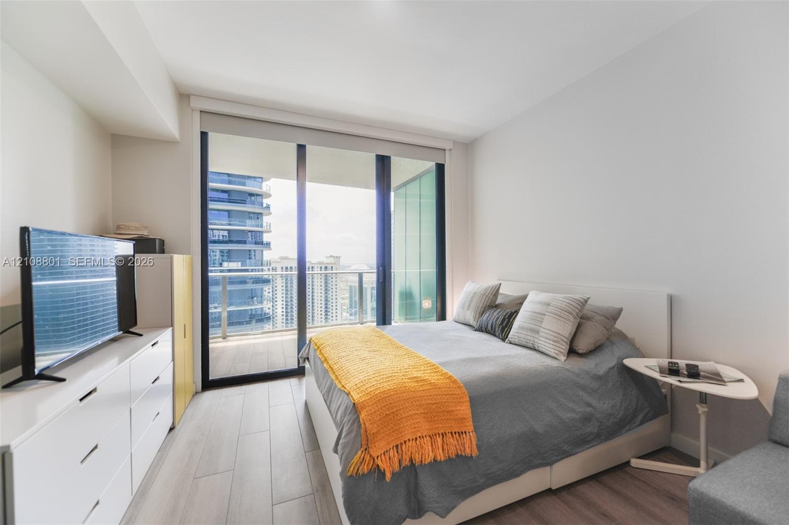 Floor-to-ceiling sliding glass door, private balcony, and light-tone wood-finish flooring