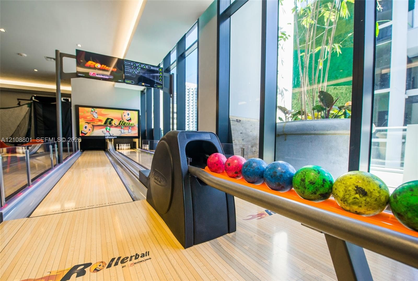 Private bowling alley featuring wood-finish lanes, floor-to-ceiling glass windows, and integrated digital scoring displays
