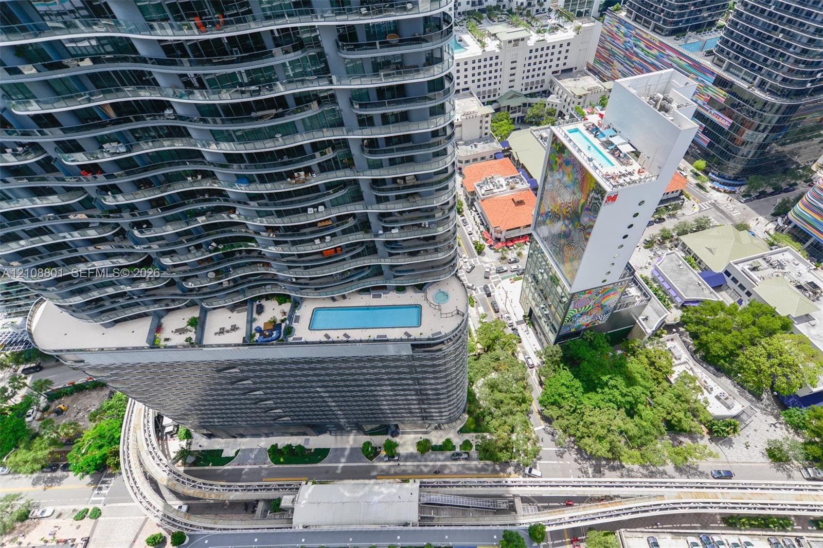High-rise residential tower featuring curved glass balconies, a landscaped elevated pool deck, and integrated parking structure