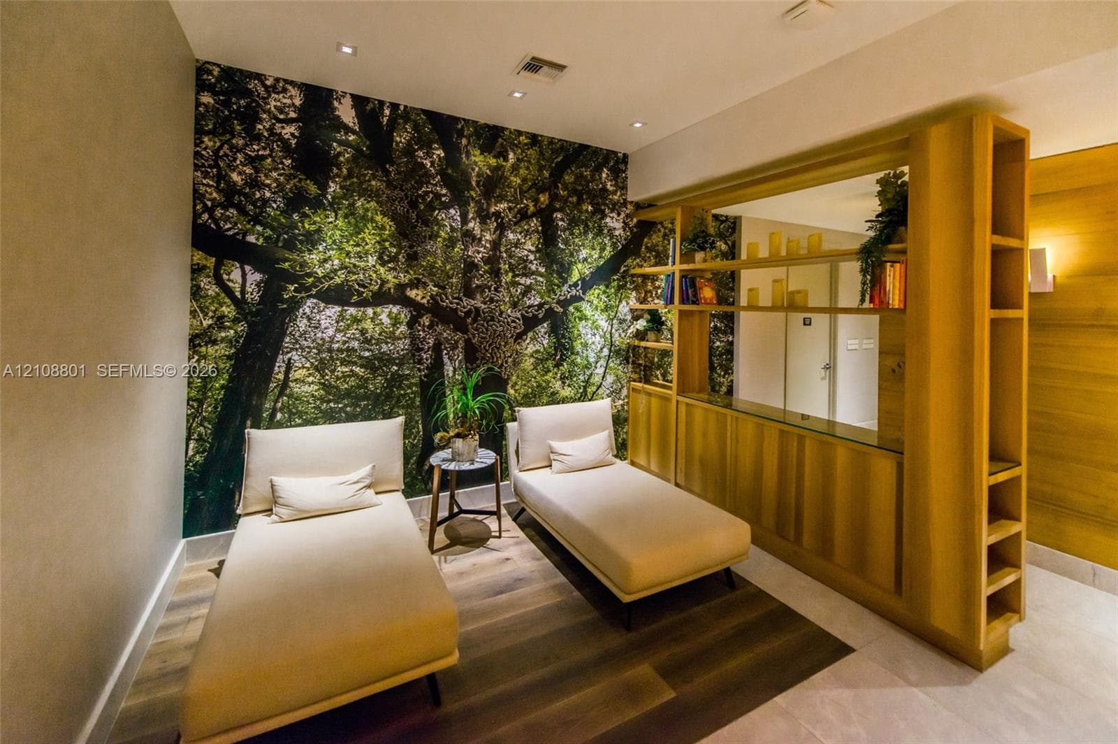 Custom wall-to-wall forest mural, floor-to-ceiling wooden built-in shelving, wood-finish flooring, recessed ceiling lighting, and natural wood wall paneling
